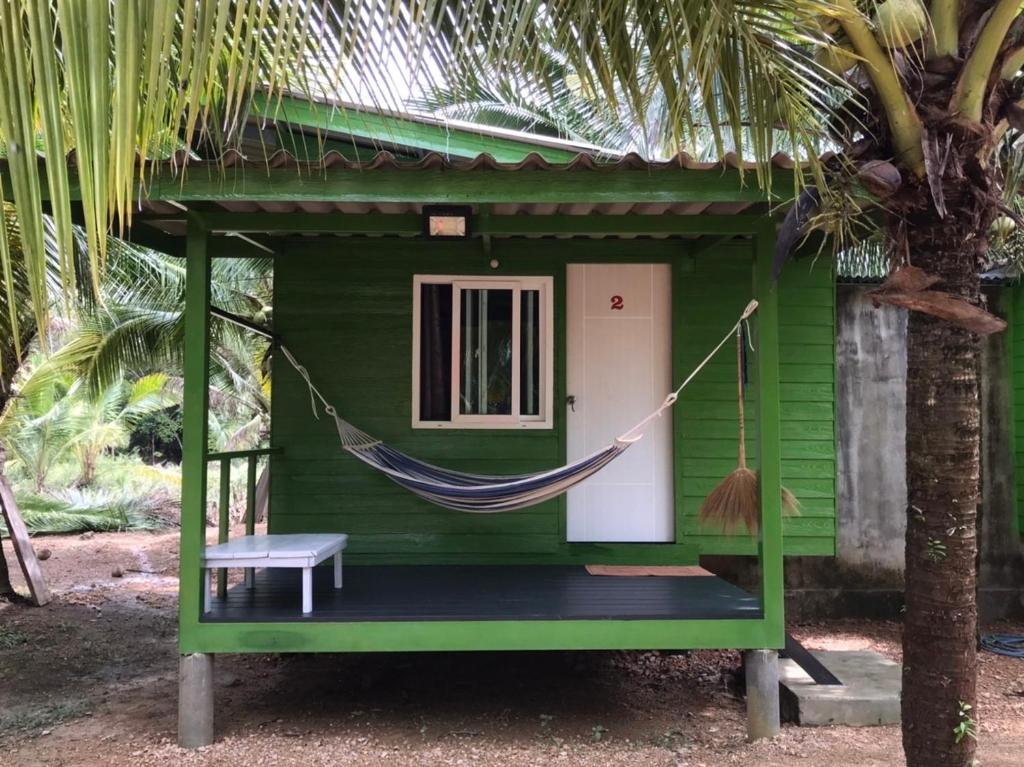 a hammock in front of a green house at Baan Suan Coconut Ko Yao Noi in Ko Yao Noi