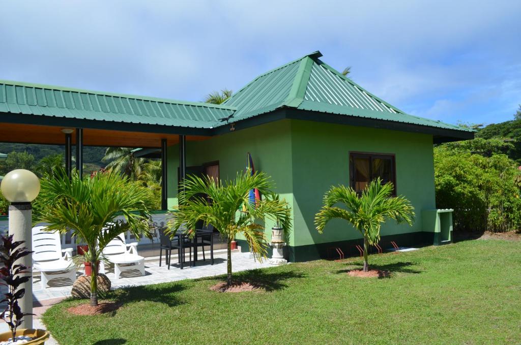 a green house with palm trees in front of it at My Angel in La Digue