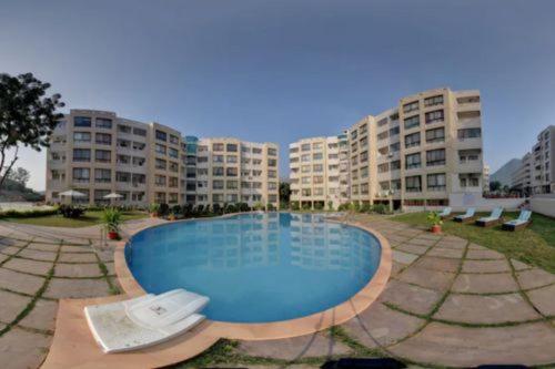 une grande piscine devant certains immeubles d'habitation dans l'établissement Avasa Homestay, à Thūr