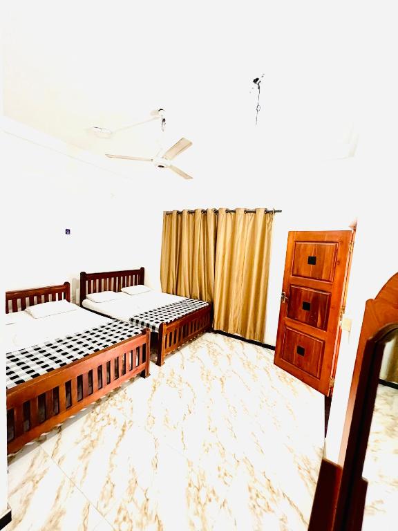a bedroom with two beds and a dresser in it at Monkey Garden Hotel in Polonnaruwa