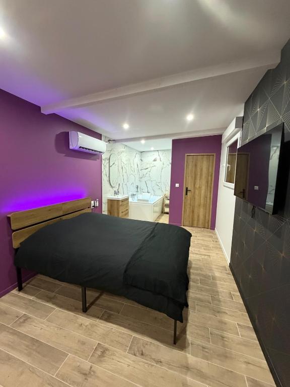 a bedroom with a bed and a purple wall at Les secrets de l Esch in Jezainville