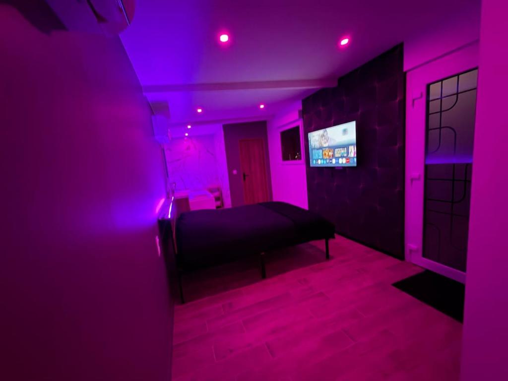 a purple room with a bed and a television at Les secrets de l Esch in Jezainville