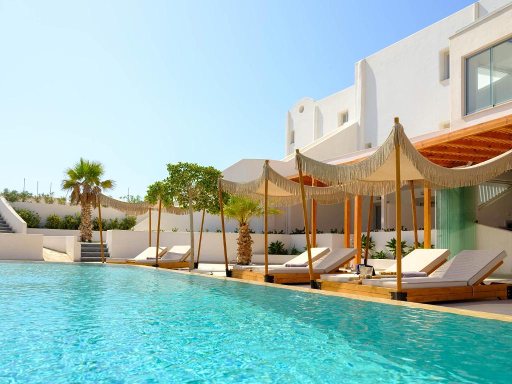 サントリーニにあるSafrani Suitesの建物の隣にプール(椅子、パラソル付)