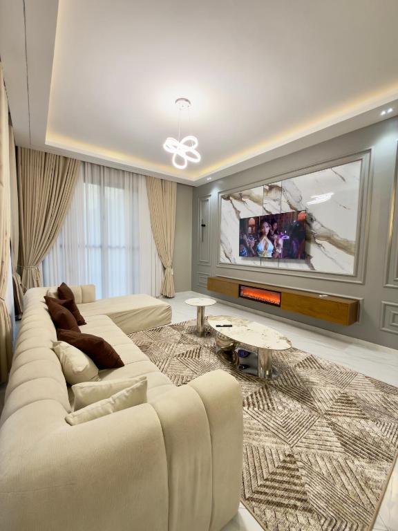 a living room with a large white couch and a tv at Urban Sage Apartments in Kampala