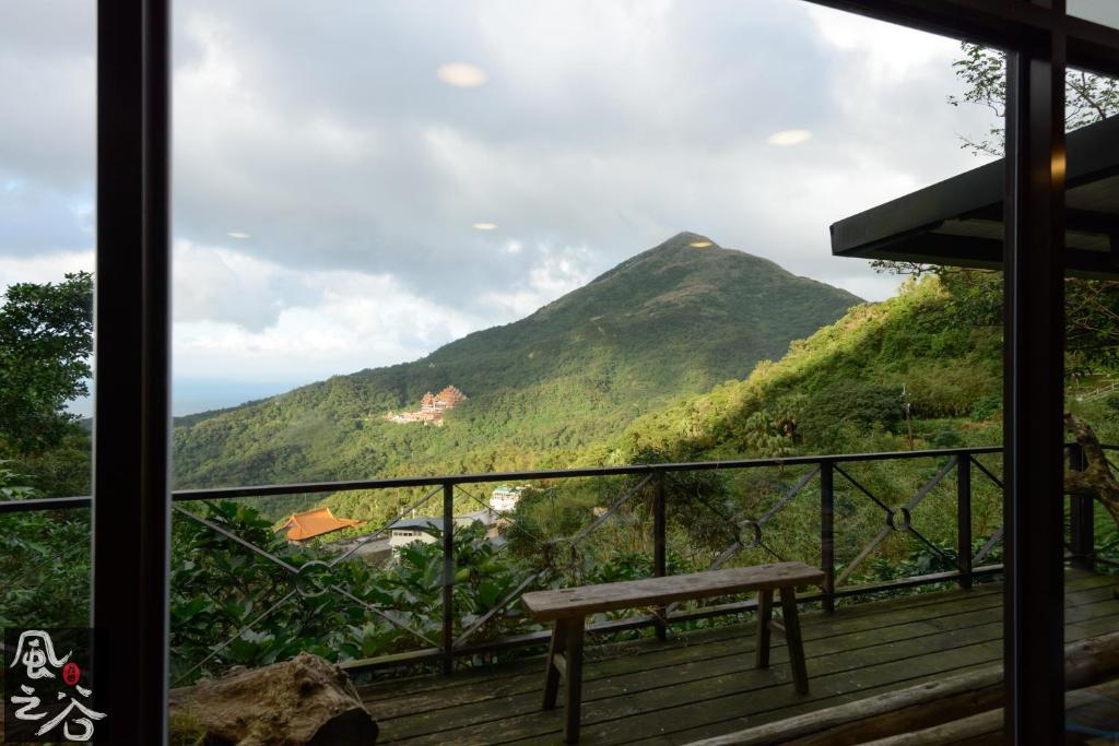 un banco en un balcón con una montaña en el fondo en Jiufen Fongigu Homestay en Jiufen