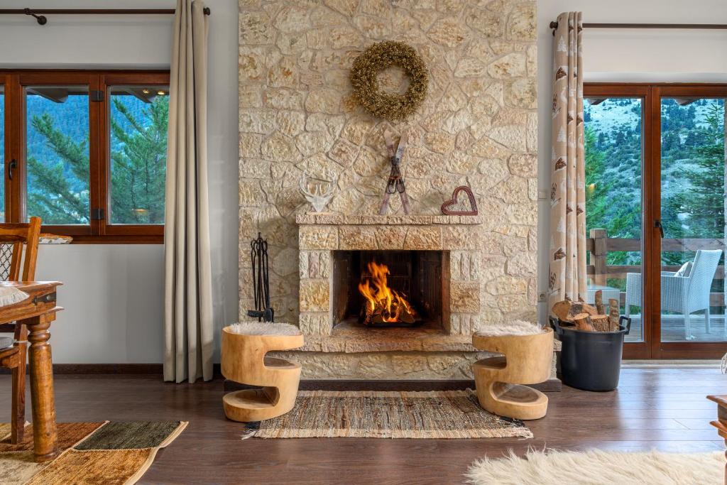 a living room with a stone fireplace with two stools at the mountain house in parnassus in Eptalofos