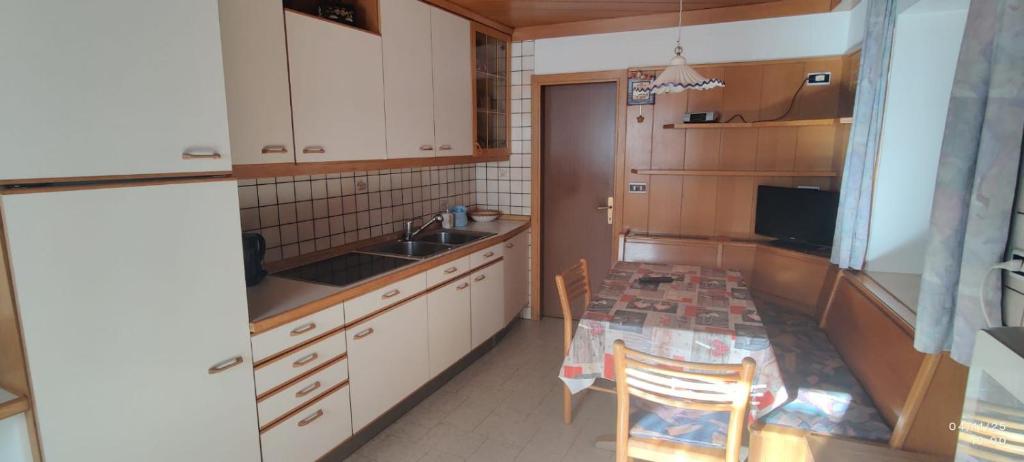 a kitchen with a table and a sink and a counter top at Casa Checolongo in Ziano di Fiemme