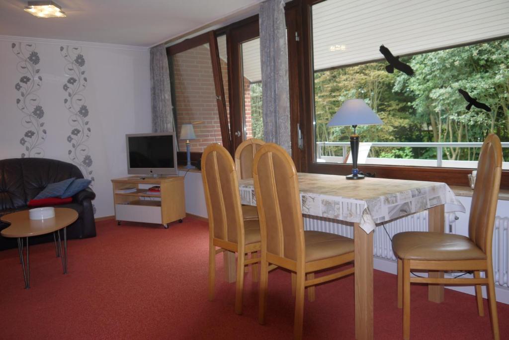 ein Wohnzimmer mit einem Tisch, Stühlen und einem TV in der Unterkunft Meeresbriese in Westerland