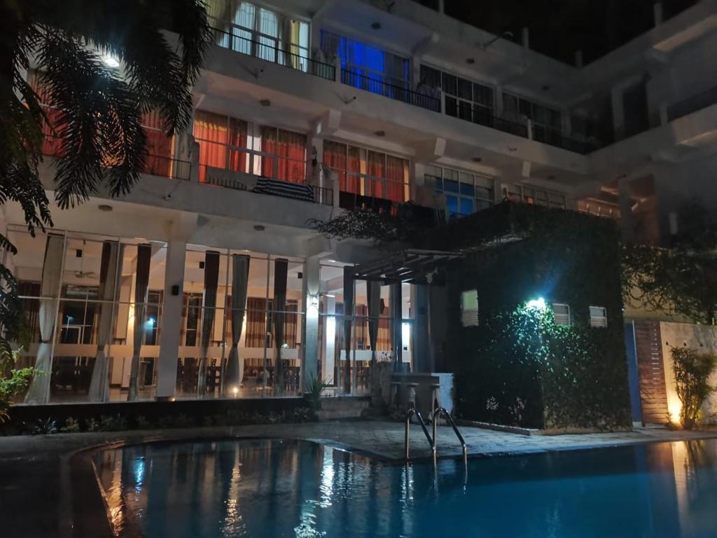 a swimming pool in front of a building at night at Ceylan Lodge Anuradhapura in Anuradhapura