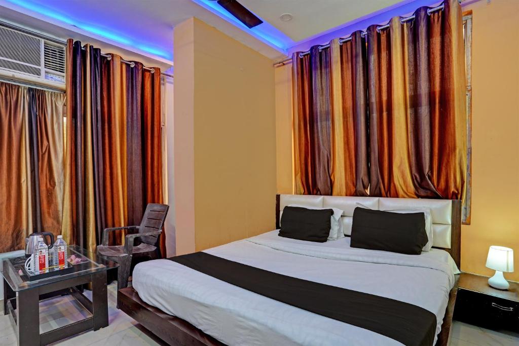 Gomti NagarHotel O Krishna Galaxy的一间卧室配有一张床、一张桌子和一些窗户