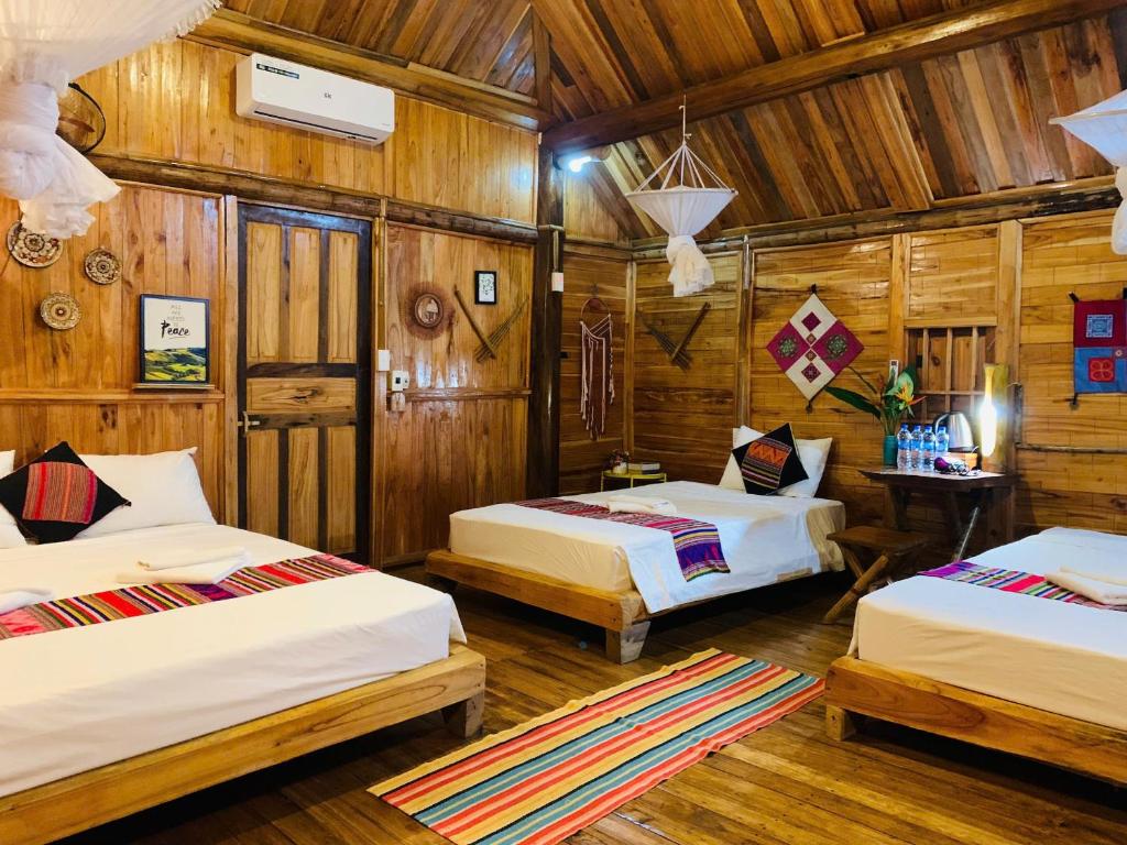 two beds in a room with wooden walls at PuLuong Bản in Lũng Tiềm