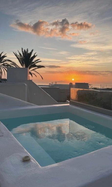 a swimming pool with the sunset in the background at Oldtown Suites Fira in Fira