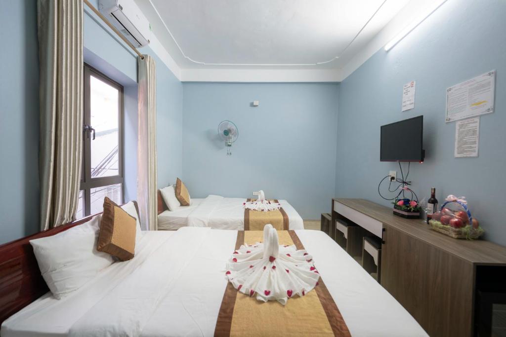 a hotel room with two beds and a television at Fancy House in Ha Long
