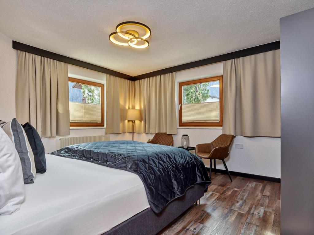 a bedroom with a large bed and two windows at Apart Helga in Oberlängenfeld