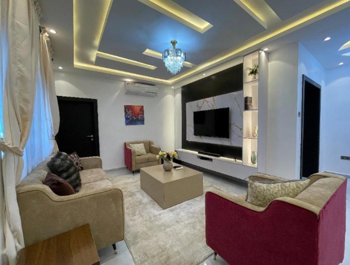 a living room with couches and a flat screen tv at HOMEWORTH SPACES - Shortlet Apartmemt in Alimosho