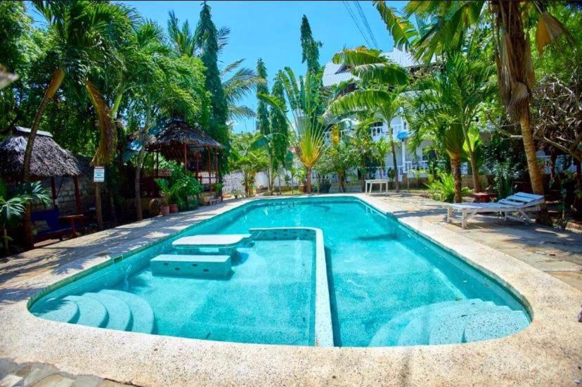 een zwembad in een resort met palmbomen bij Karean Studio suites in Ukunda