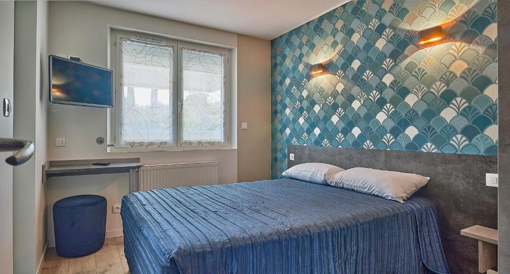 Un dormitorio con una cama con una colcha azul. en Hotel Restaurant L'Atlantique, en Saint-Jean-de-Monts