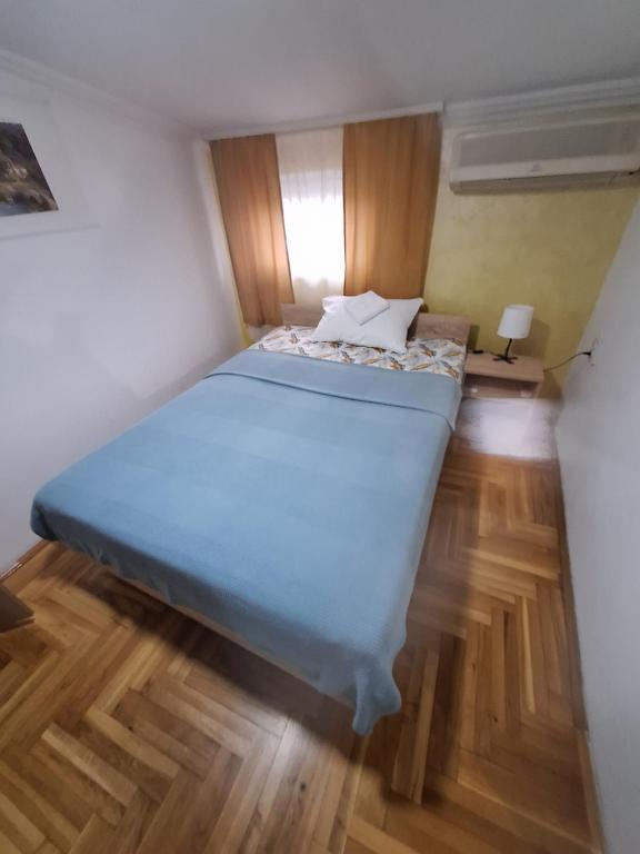 Una cama grande en una habitación pequeña con suelos de madera. en Rooms3, en Beograd