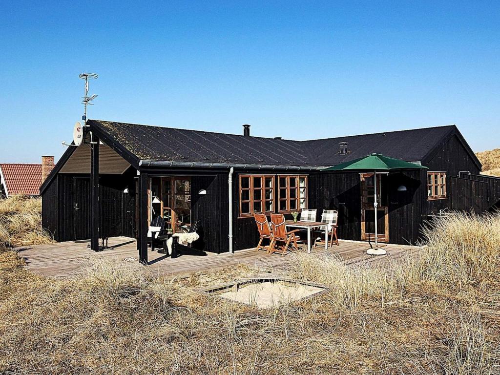 a black house with a table and chairs on a deck at Cozy Retreat by the Sea - By Traum Ferienwohnungen in Hvide Sande