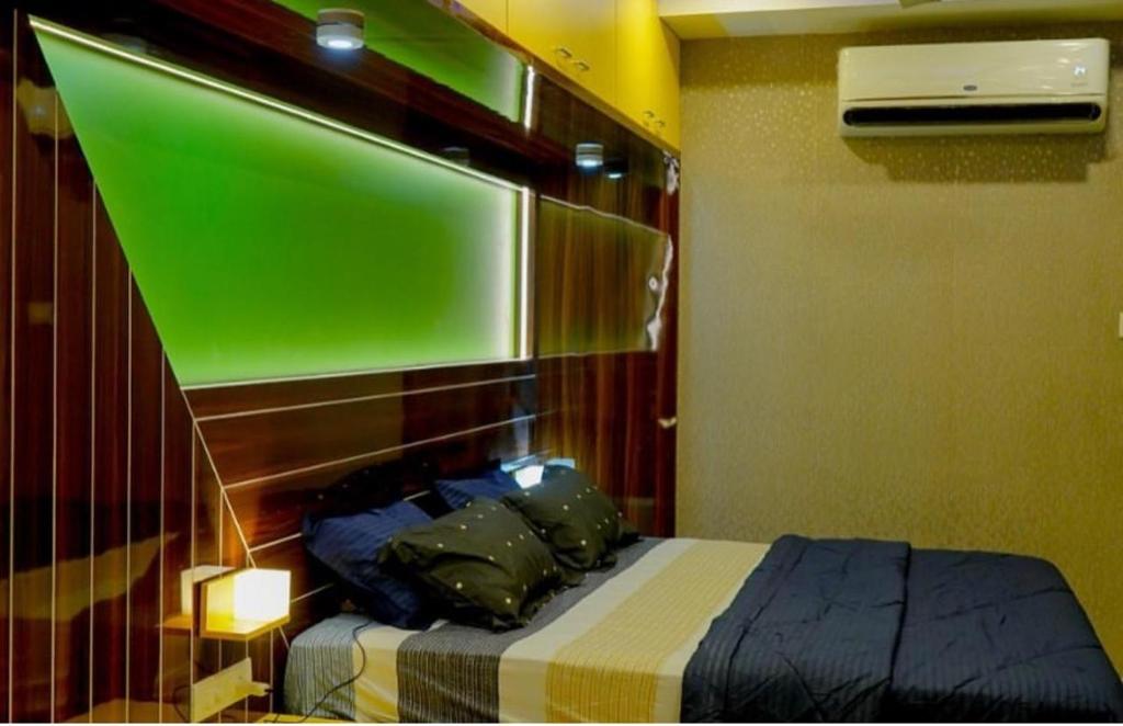 a bedroom with a bed with a green screen above it at SIS Acropole in Golden Rock