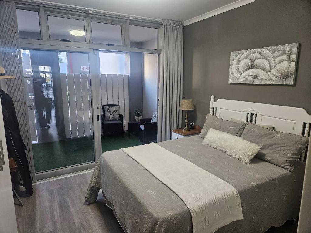 een slaapkamer met een groot bed en een groot raam bij Seaside Charm in Bloubergstrand
