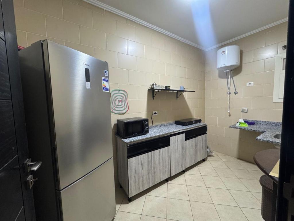 Una cocina con refrigerador de acero inoxidable en una habitación. en Zayed Elite Retreat pool, garden & breeze, en Seis de Octubre