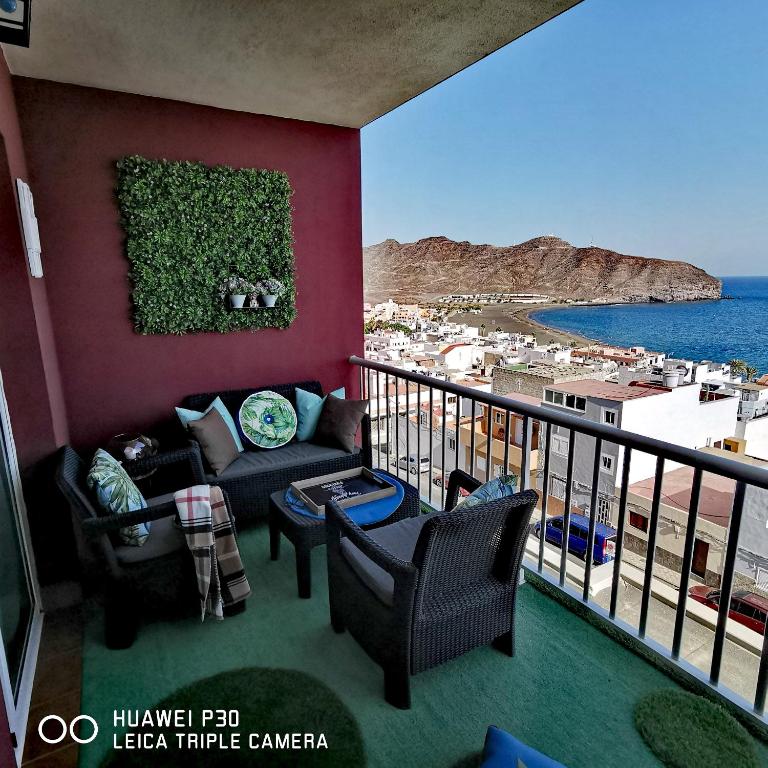 a balcony with a couch and chairs and the ocean at Wind Rose Duplex in Gran Tarajal