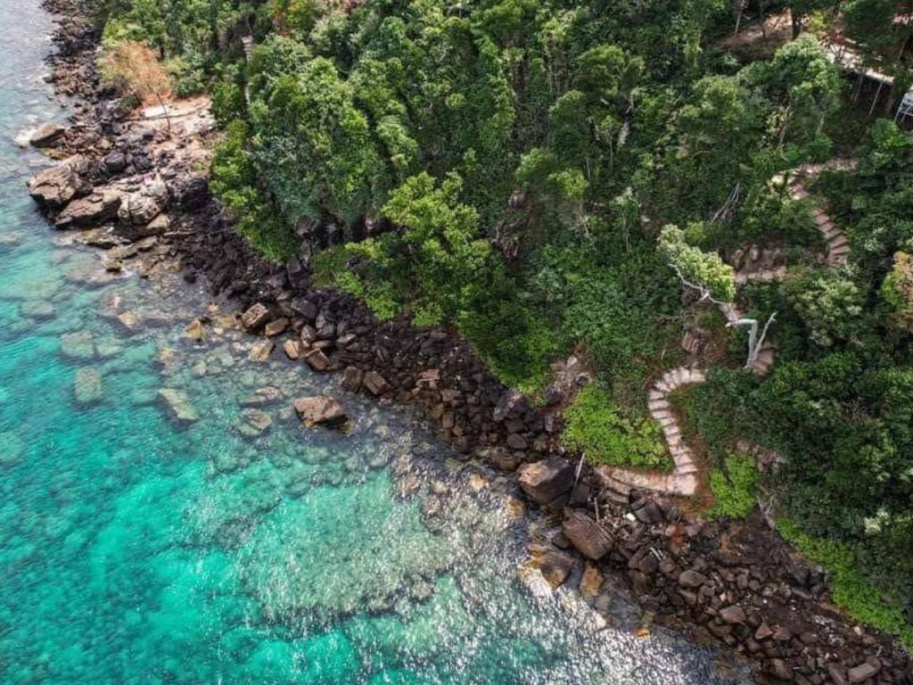 an aerial view of a rocky shore with blue water at The Cliff Hostel, M'Pay Bay in Koh Rong Sanloem