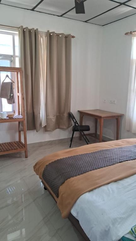 Un dormitorio con una cama y un escritorio y una ventana. en Mh homestay, en Bīr