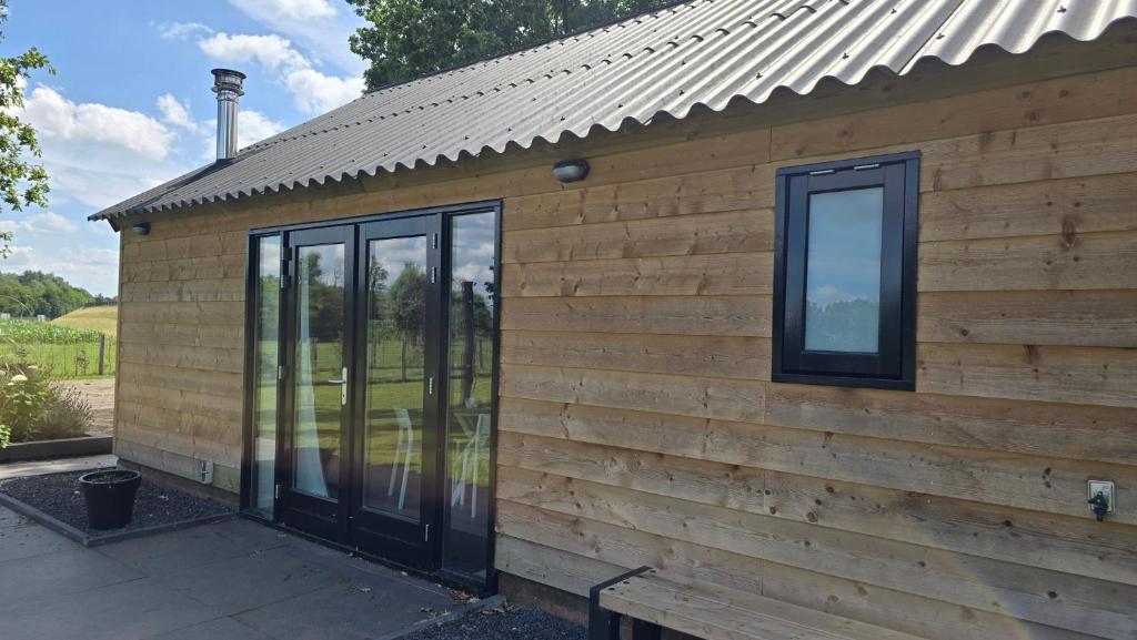 a wooden cabin with a metal roof at Lodge Klein Ganseij in Olst