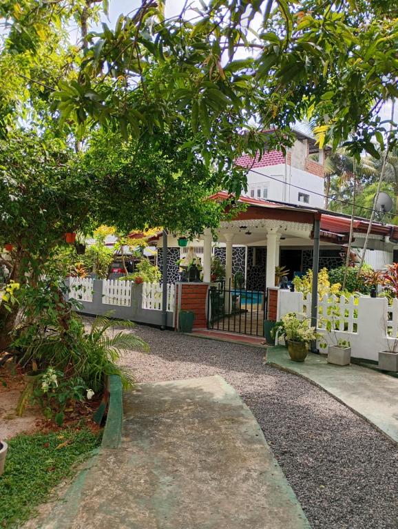 a house with a white fence and a yard at Villa Onus in Aluthgama