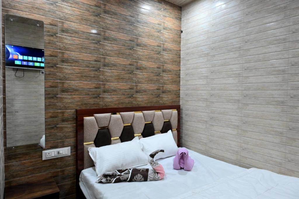 a bedroom with a bed with white sheets and pink shoes at Hotel Bhagirath in Mumbai