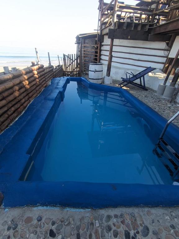 a large blue swimming pool next to the beach at Máncora Hostel Restocafebar in Máncora