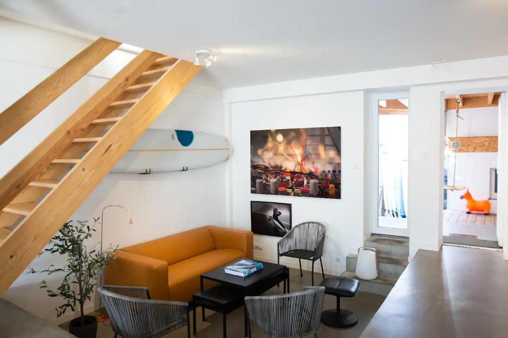 a living room with a couch and a surfboard on the wall at Koala Surf House, en bord d'Océan, planches de surf et skates à disposition in Hossegor