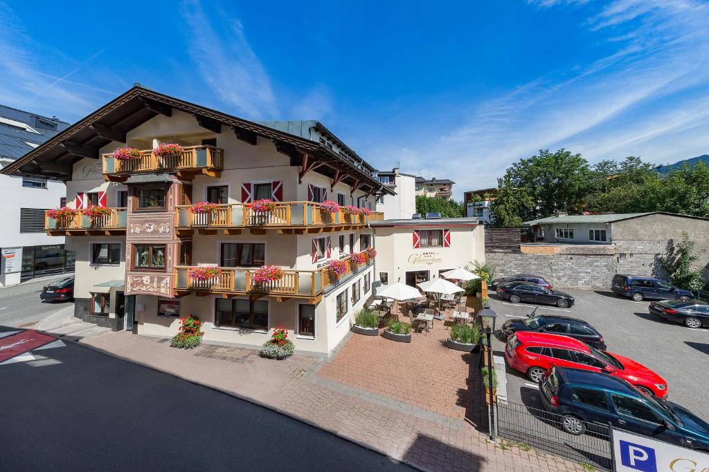 ein Gebäude mit einem roten Auto auf einem Parkplatz in der Unterkunft Hotel Glasererhaus in Zell am See