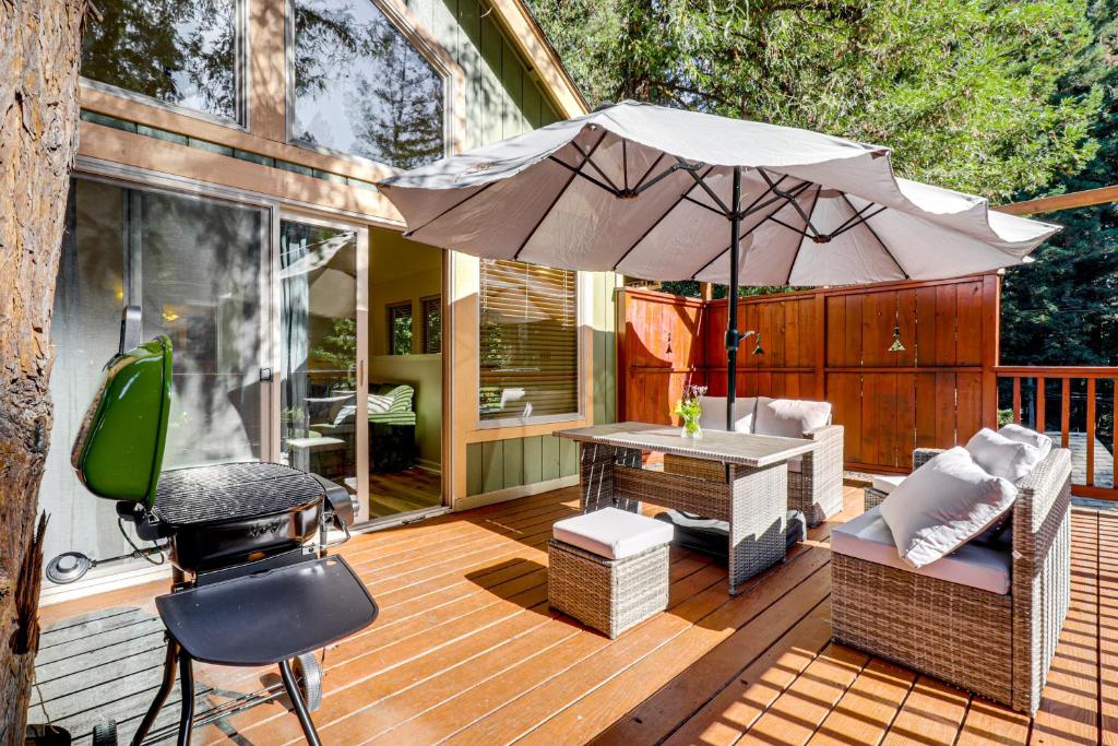 eine Terrasse mit einem Tisch, einem Sonnenschirm und einem Grill in der Unterkunft Redwoods Escape with Hot Tub Near Russian River! in Rio Nido