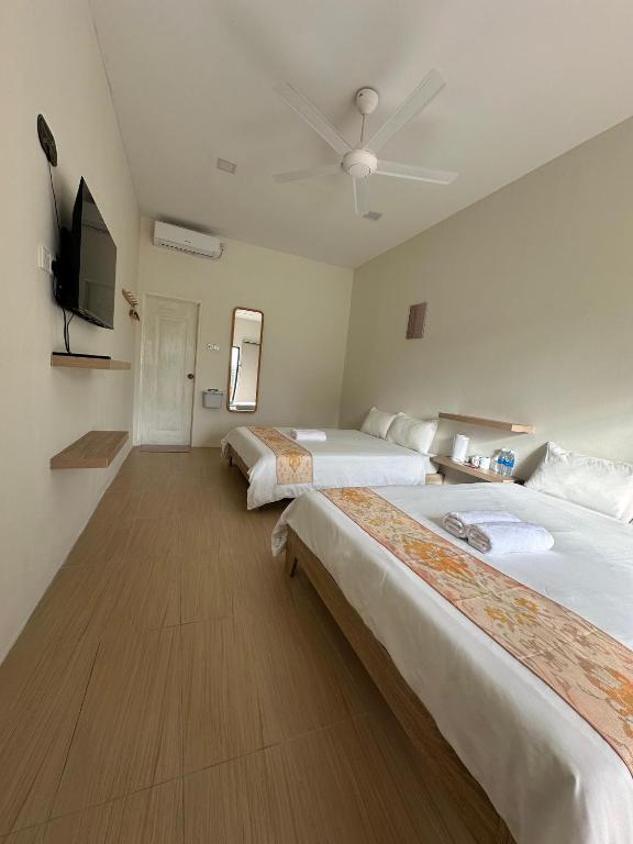 a hotel room with two beds and a flat screen tv at Cerya Kampung Inn in Cherating