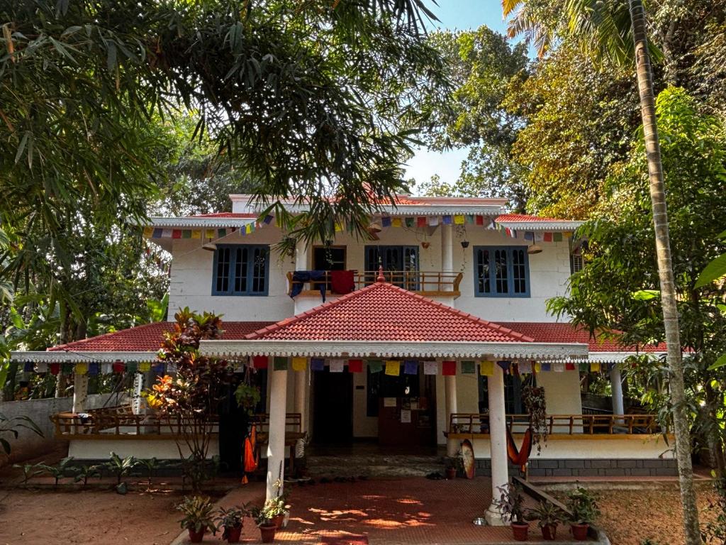 a white house with a red roof at Barefoot Hostels, Varkala in Varkala
