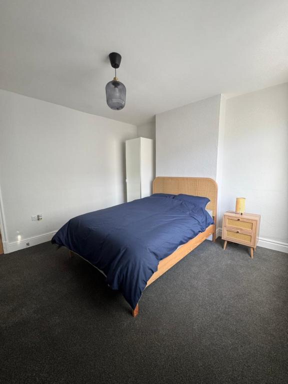 レスターにあるSerenity LTDのベッドルーム(青いベッド1台、ナイトスタンド付)