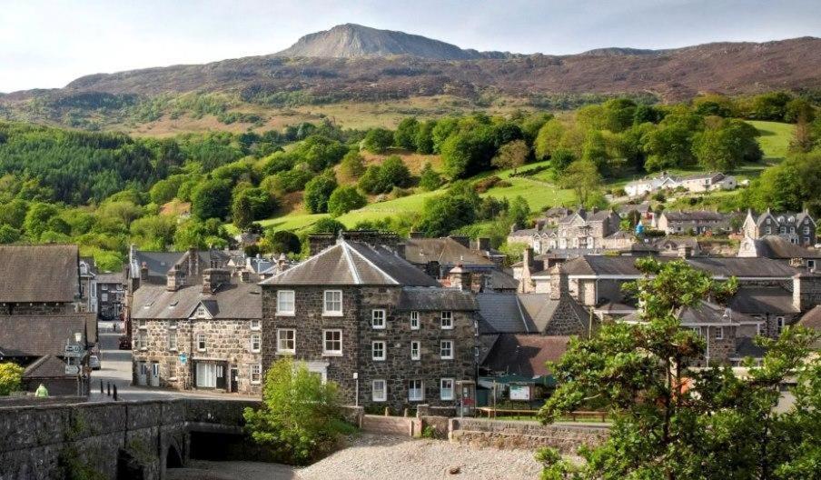 una ciudad en las colinas con una montaña en el fondo en Glyder Flat - North Wales, en Dolgellau