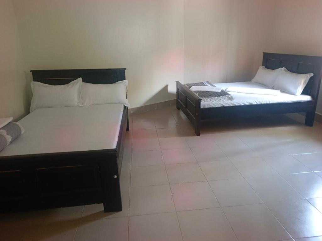 two beds sitting in a room with at Guardian Motel Kasese in Kasese