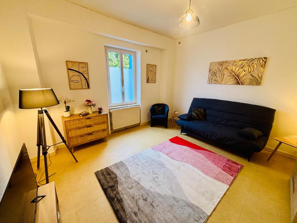una sala de estar con un sofá y una mesa en Le pied à terre - Centre ville - Montceau-les-mines, en Montceau-les-Mines