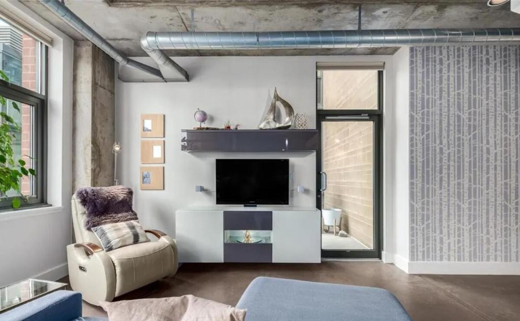 een woonkamer met een tv en een stoel bij Union Station downtown and gameday retreat! in Denver