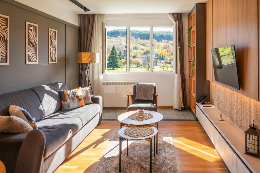 a living room with a couch and a tv at Modern Mountain - Comfort Apartment in Kolašin