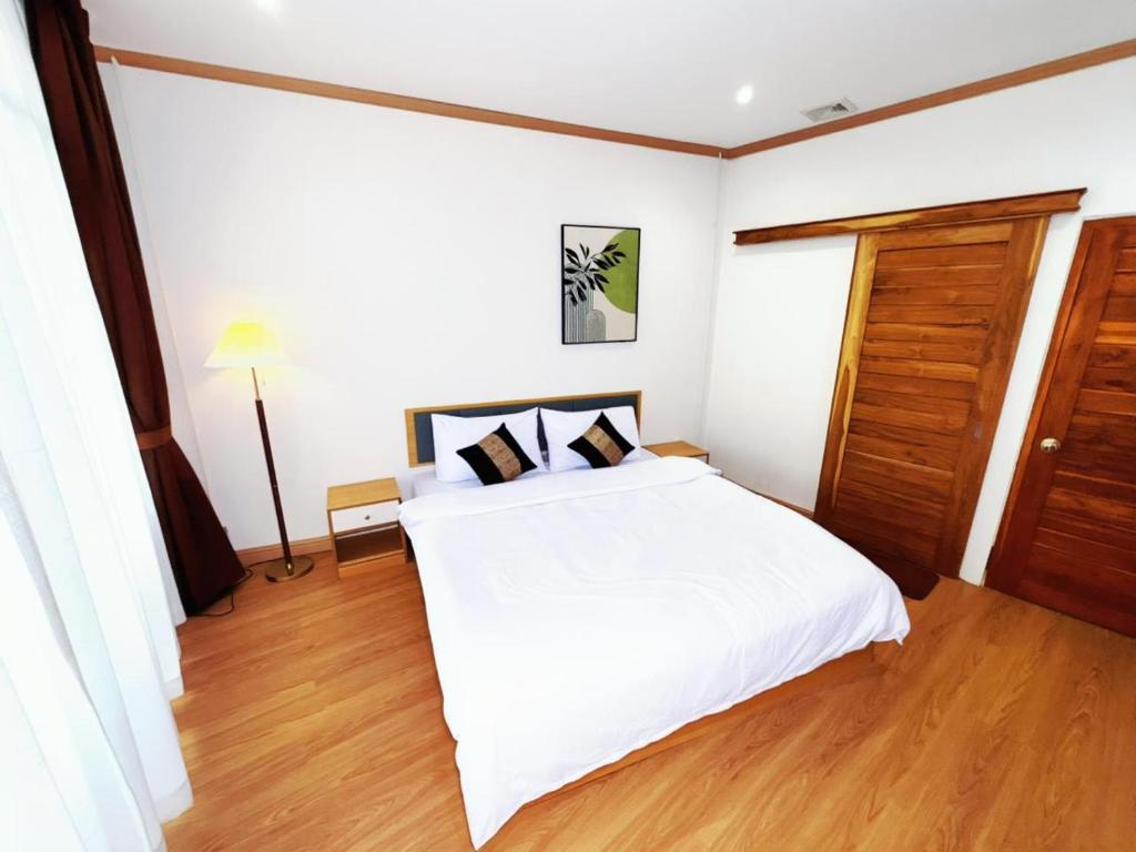 a bedroom with a white bed and a wooden floor at Demi Cafe and Hostel in Vientiane
