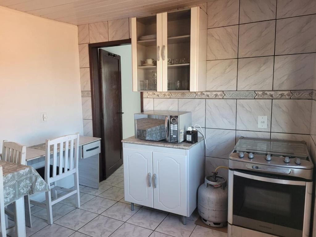 une cuisine avec des armoires blanches et un four à plaques de cuisson dans l'établissement Kit net familia, à São Francisco do Sul