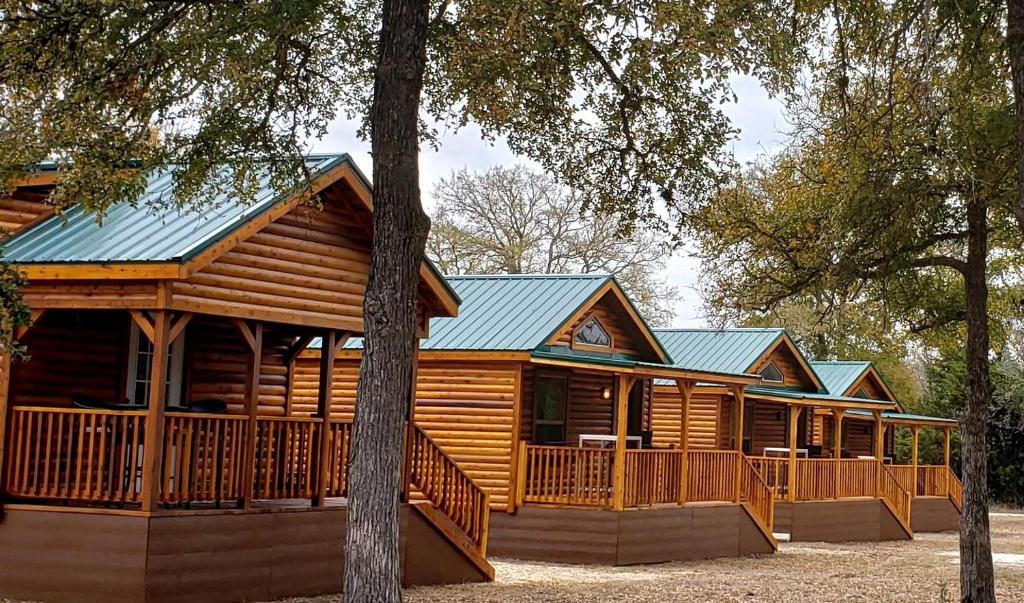 a large log cabin with a porch and trees at Texas State Glamping in this Charming Cabin Rental for Six in Pipe Creek in Pipe Creek