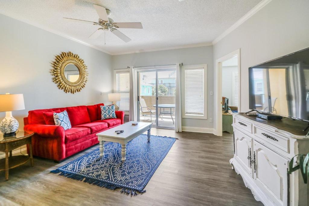 a living room with a red couch and a table at Sandpiper #108 in Tybee Island