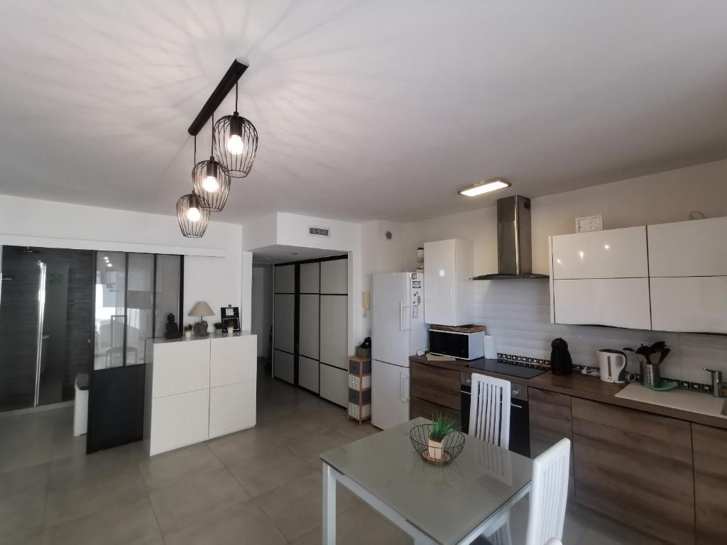 una cucina con armadi bianchi e un tavolo di Magnifique studio au pied des plages a Cannes