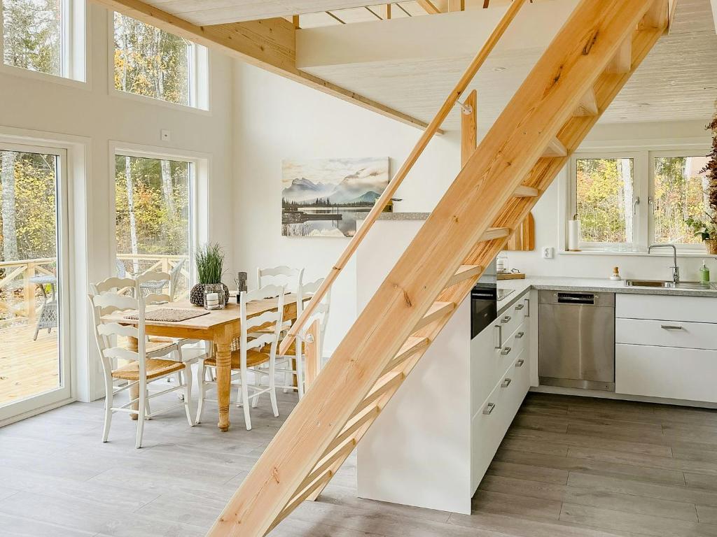 a kitchen and dining room with a wooden staircase at Modern Loft House In The Woods Near Gullabo in Gullabo